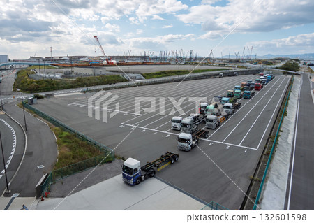 在大阪港夢島的貨櫃碼頭,一排拖車正在等待裝卸,遠處可以看到世博會場館(物流、貿易、2024 年議題)。 在大阪港夢島的貨櫃碼頭,一排拖車正在等待裝卸,遠處可以看到世博會場館(物流、貿易、2024 年議題)。 132601598