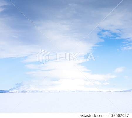 一幅簡潔的風景畫，由神秘的雲朵、蔚藍的天空、白雪皚皚的田野和白雪皚皚的山峰組成。 132602017