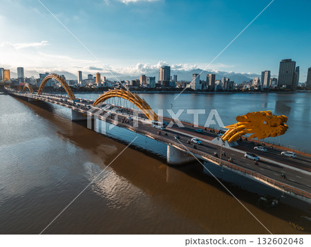 Golden Dragon Bridge over Han River in Da Nang at sunset, Iconic Vietnamese landmark spanning urban waterway with city skyline view Golden Dragon Bridge over Han River in Da Nang at sunset, Iconic Vietnamese landmark spanning urban waterway with city skyline view 132602048