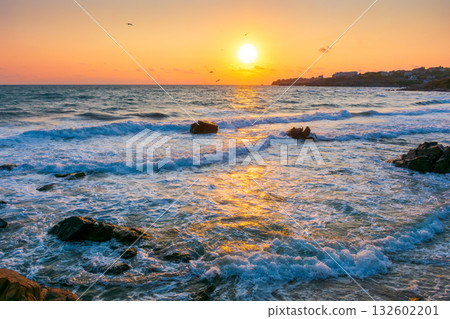 beautiful sunrise at the sea beach. sandy coast with rock. summer vacation background. sun over horizon. calm waves under orange sky in morning light. amazing seascape for best memories from bulgaria beautiful sunrise at the sea beach. sandy coast with rock. summer vacation background. sun over horizon. calm waves under orange sky in morning light. amazing seascape for best memories from bulgaria 132602201