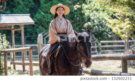 一位身著和服、微笑的女子正在體驗騎馬。 132602251
