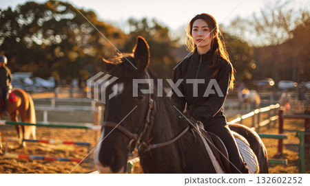 日落時分，一位女子在騎馬場上騎馬。 132602252