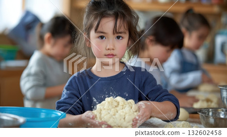A girl with a serious expression holding bread dough in a bread-making class A girl with a serious expression holding bread dough in a bread-making class 132602458