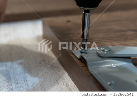 Assembling furniture at home using an electric screwdriver Assembling furniture at home using an electric screwdriver 132602541