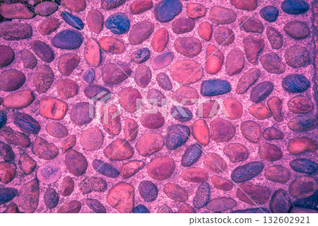 Pebbles embedded in a concrete wall. Burgundy pebble texture. Abstract stone background. Burgundy color 132602921