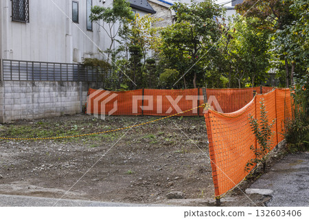 Vacant lot in a residential area and an orange safety fence 132603406