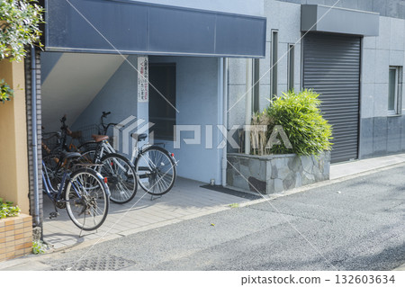 View of the apartment complex entrance and bicycle parking lot during the day View of the apartment complex entrance and bicycle parking lot during the day 132603634