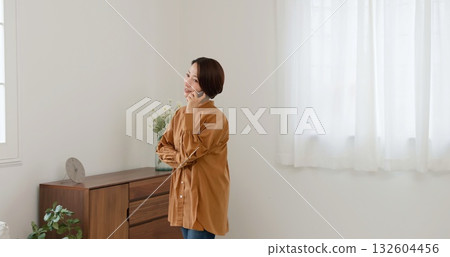 Woman on the phone by the window image 132604456