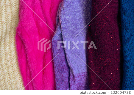 Stack of knitted sweaters. Different knitting patterns. Warm handmade clothes. Knitted sweater cardigans. Craft product concept. Winter fashion. Cozy woven clothing. Knitted fashion. Knitting hobby. 132604728