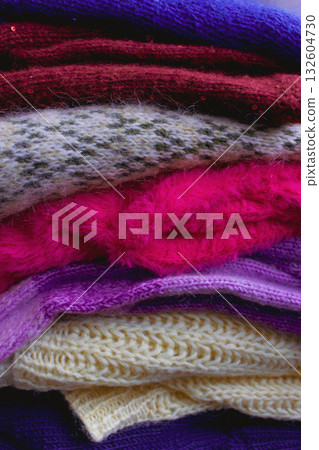 Stack of knitted sweaters. Different knitting patterns. Warm handmade clothes. Knitted sweater cardigans. Craft product concept. Winter fashion. Cozy woven clothing. Knitted fashion. Knitting hobby. 132604730