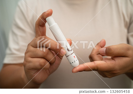 Asian woman self testing to check blood sugar level diabetes by digital lancet on finger at home. 132605458