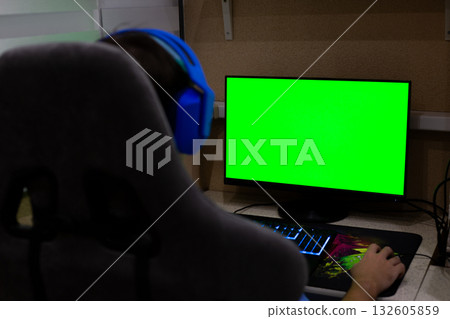Concept for working long hours at computer at home. Man wearing headphones solves office tasks while working on modern computer remotely from home in cozy atmosphere of his apartment 132605859