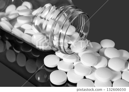 White pills falling out of a transparent plastic bottle White pills falling out of a transparent plastic bottle 132606030