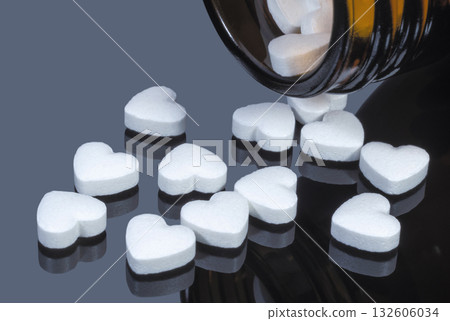 White pills in the form of hearts falling out of a glass bottle White pills in the form of hearts falling out of a glass bottle 132606034