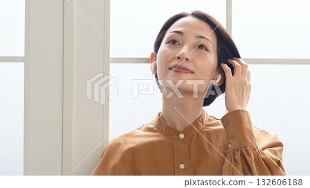 一位女士在窗邊聽音樂或聽收音機 132606188