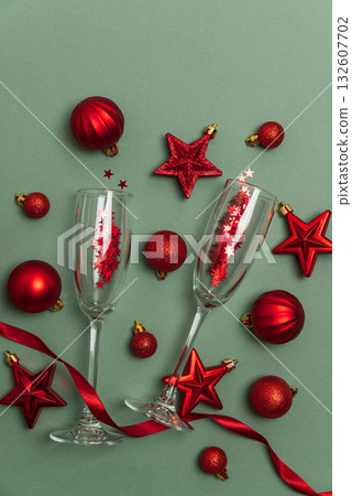 Champagne Flutes with Red Christmas Ornaments and Ribbon on Green Background Champagne Flutes with Red Christmas Ornaments and Ribbon on Green Background 132607702