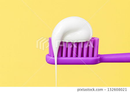 Toothpaste on purple toothbrush against yellow background. dental hygiene, freshness, oral care, and morning routine. Toothpaste on purple toothbrush against yellow background. dental hygiene, freshness, oral care, and morning routine. 132608021