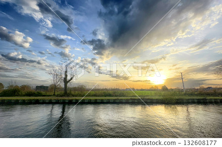 Experience the stunning beauty of a vibrant sunset over a calm and tranquil river landscape 132608177