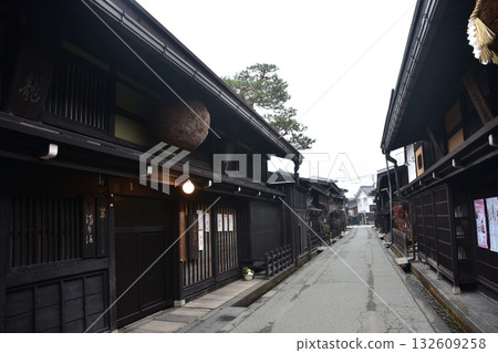 日本岐阜縣高山市的古老街景。一家用杉木球裝飾的清酒店和一棟充滿歷史氣息的老房子。高山春季祭典期間的清晨景象。 日本岐阜縣高山市的古老街景。一家用杉木球裝飾的清酒店和一棟充滿歷史氣息的老房子。高山春季祭典期間的清晨景象。 132609258