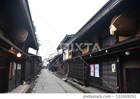 日本岐阜縣高山市的古老街景。一家用杉木球裝飾的清酒店和一棟充滿歷史氣息的老房子。高山春季祭典期間的清晨景象。 日本岐阜縣高山市的古老街景。一家用杉木球裝飾的清酒店和一棟充滿歷史氣息的老房子。高山春季祭典期間的清晨景象。 132609261