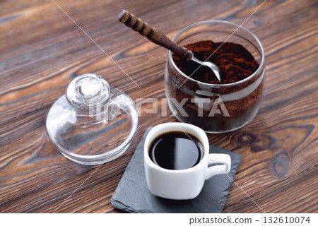 coffee in a cup on a stone stand ground coffee in a glass jar vintage coffee spoon, wooden natural background 132610074