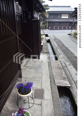 日本岐阜縣的春天。高山市中心的古老街道。歷史悠久的日式房屋和小水道。路邊美麗的盆栽。 132610954