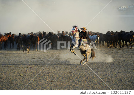 A cowboy chasing a herd of horses A cowboy chasing a herd of horses 132611127