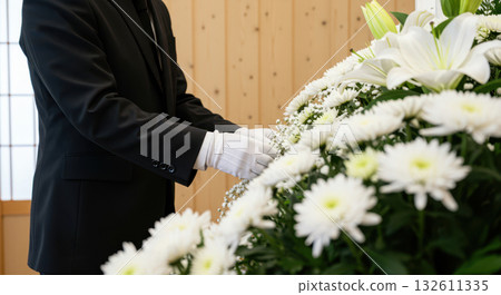 Funeral staff wearing white gloves arranging flowers (AI-generated image) Funeral staff wearing white gloves arranging flowers (AI-generated image) 132611335