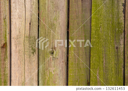 A Beautifully Weathered Wooden Fence Covered in Lush Green Moss and Rich Textures 132611453
