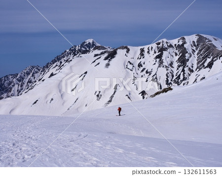 Spring skiing on the Tateyama Kurobe Alpine Route - Mountain skiers skiing down Murododaira with a view of Mount Tsurugidake 132611563