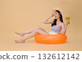 Summer vacation travel woman relaxing on orange inflatable ring holding cocktail on beige studio background with copy space ideal for travel ads and lifestyle mockups 132612142