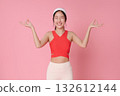 Fitness woman meditation pose with OK mudra on pink background smiling in red sports top for wellness yoga balance and healthy lifestyle advertising 132612144