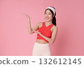 Fitness asian woman presenting copy space on pink background in red sports top for wellness advertising gym promotion and healthy lifestyle banner mockup 132612145