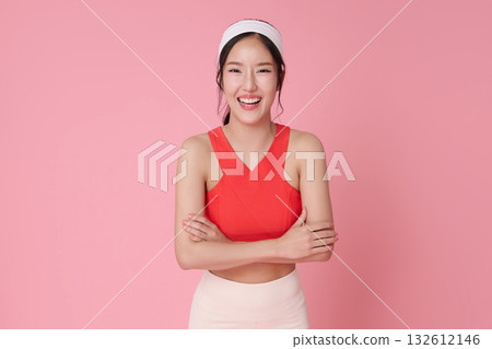 Fitness woman on pink background in red sports top smiling with arms crossed for wellness active lifestyle athleisure advertising and healthy gym marketing with copy space 132612146