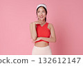 Fitness model Asian woman on pink background in red sports top smiling thinking for wellness and active lifestyle athleisure advertising 132612147