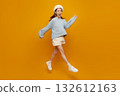 Jumping woman on yellow background, cheerful Asian girl in blue sweater and beret leaping midair copy space for fashion, lifestyle, youth, happiness, promotion, and social media banner. 132612163