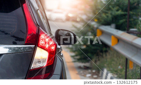 Rear side of grey car close up taillight on the road. Traffic barrier with grass and trees growing on the sides. Blurred of many car on the opposite road. Rear side of grey car close up taillight on the road. Traffic barrier with grass and trees growing on the sides. Blurred of many car on the opposite road. 132612175
