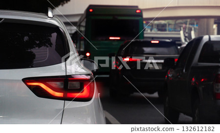 Rear side of white car with turn on brake light. Traffic jam on the asphalt road in the ciy at evening. 132612182