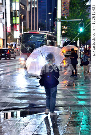 雨夜,銀座街頭,一位女士撐著塑膠傘行走。 雨夜,銀座街頭,一位女士撐著塑膠傘行走。 132612422