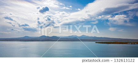 A beautiful blue sky with a few clouds and a calm ocean 132613122