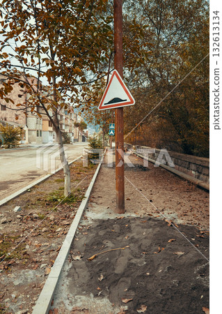 A sign on a pole in a city street warns of a steep drop 132613134