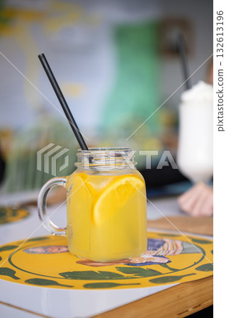 A glass of orange juice with a straw in it A glass of orange juice with a straw in it 132613196