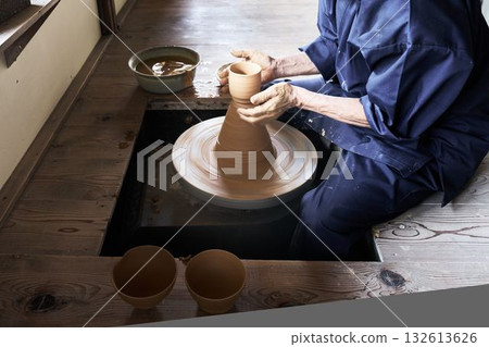 A potter using a potter's wheel to shape a piece 132613626