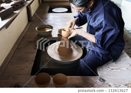 A veteran craftsman shaping a piece using a potter's wheel A veteran craftsman shaping a piece using a potter's wheel 132613627