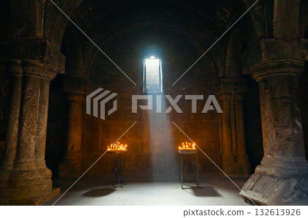 A dark room with a window and two candles lit 132613926