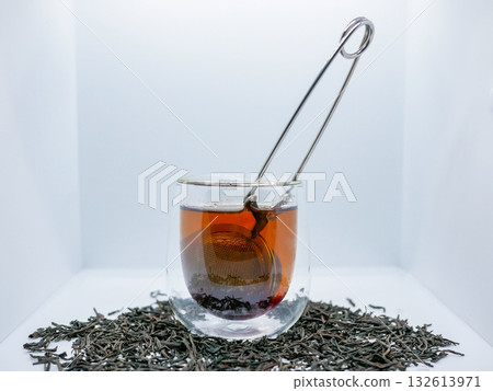 Glass Cup of Black Tea with Infuser and Loose Leaves on White Background Glass Cup of Black Tea with Infuser and Loose Leaves on White Background 132613971