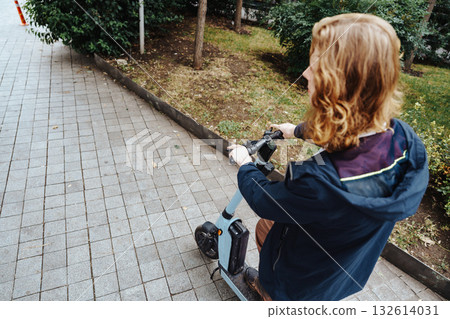 Man rides electric scooter on paved path through greenery in urban park during daytime Man rides electric scooter on paved path through greenery in urban park during daytime 132614031