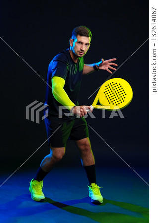 Practicing padel with a bright racket in a dramatic lighting setting 132614067