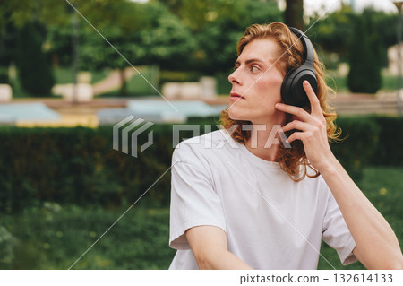 Listening to music while relaxing in a peaceful outdoor park setting Listening to music while relaxing in a peaceful outdoor park setting 132614133
