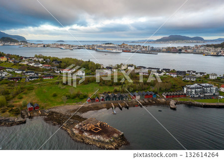 Beautiful panoramic view of Alesund coastal town featuring bright houses, tranquil sea reflections, and misty hills in Norway.  132614264